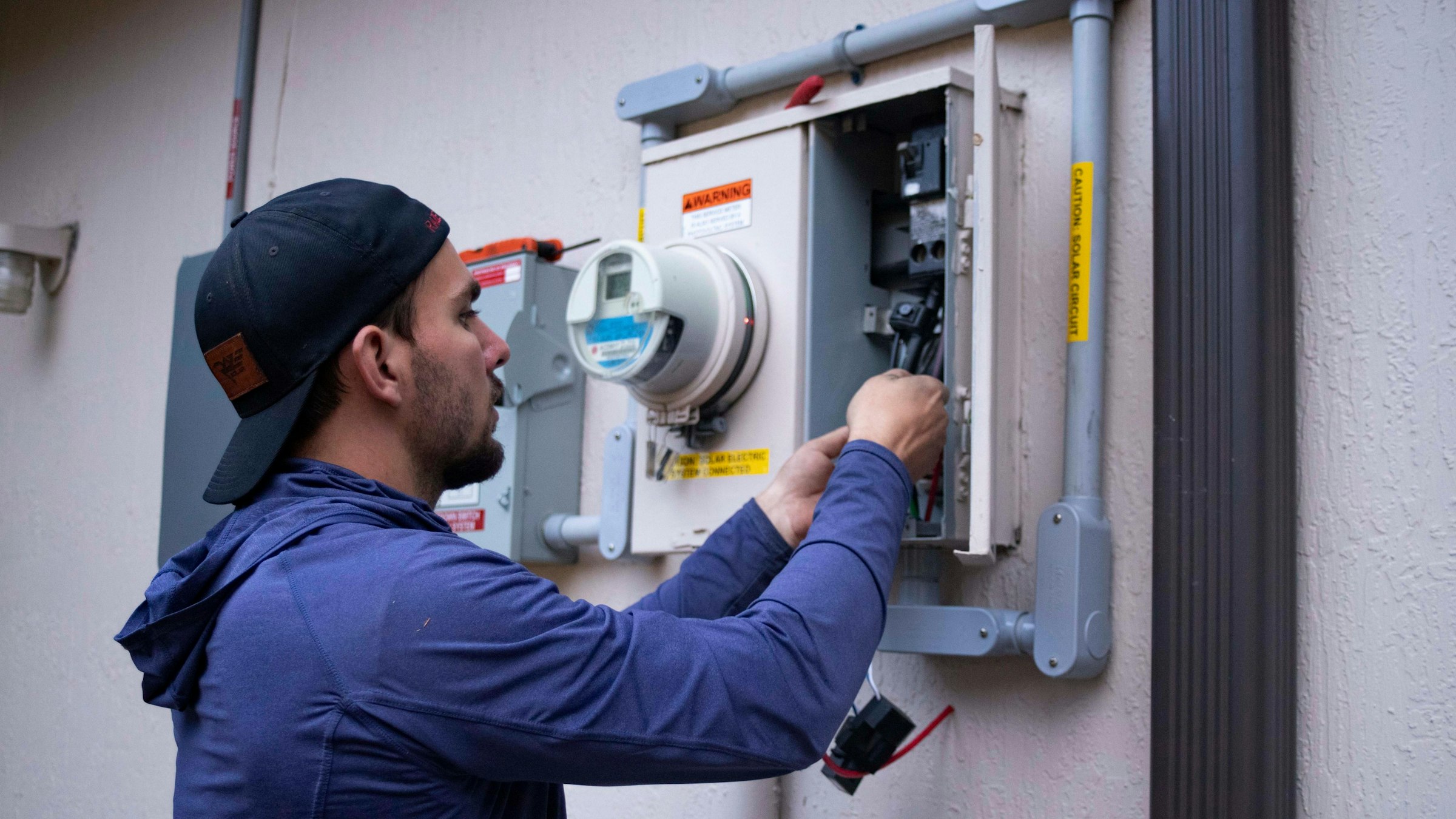Electrician working on a wall-mounted meter board
